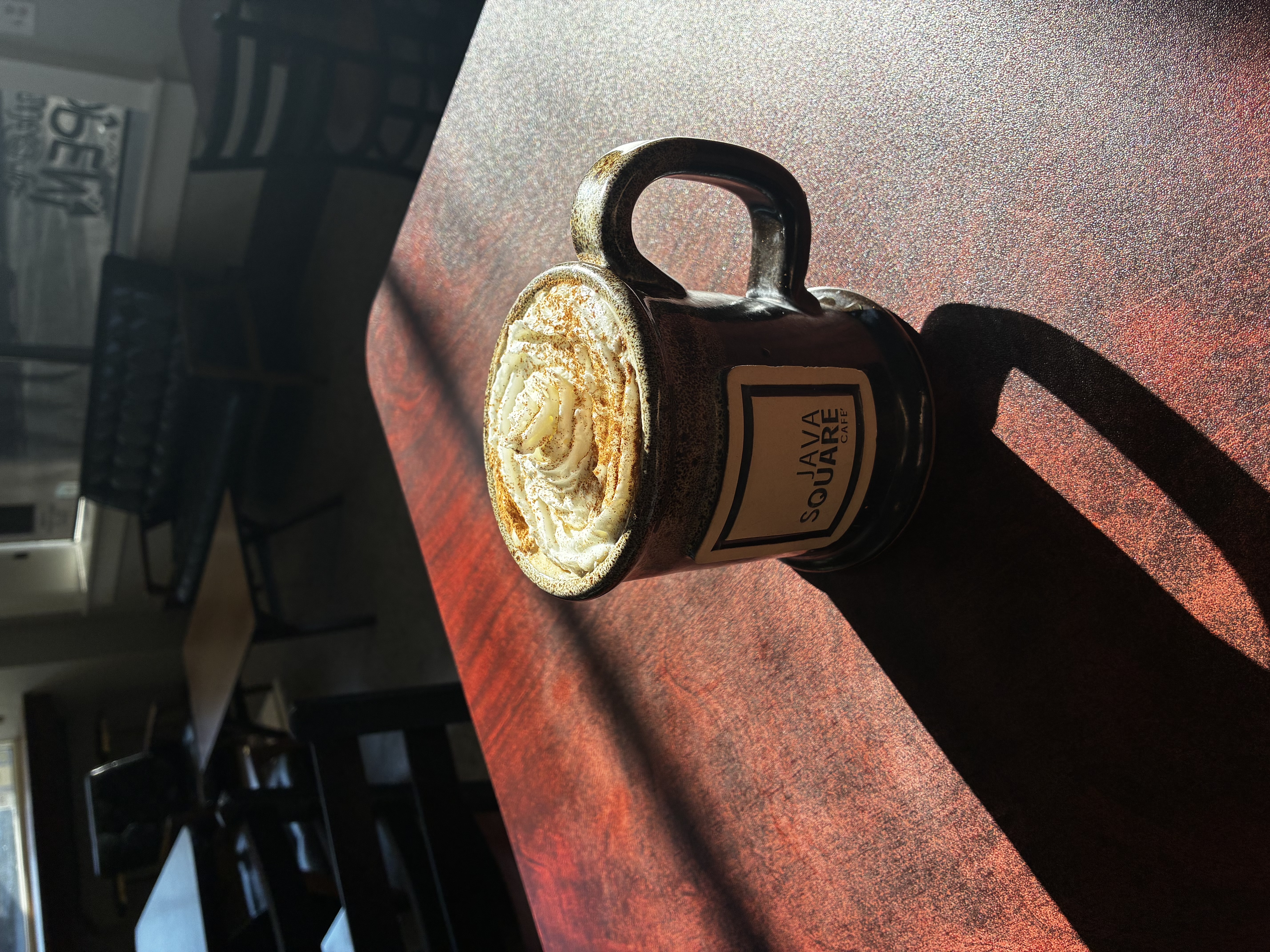 Cafe detail — coffee cup on a wooden bar
